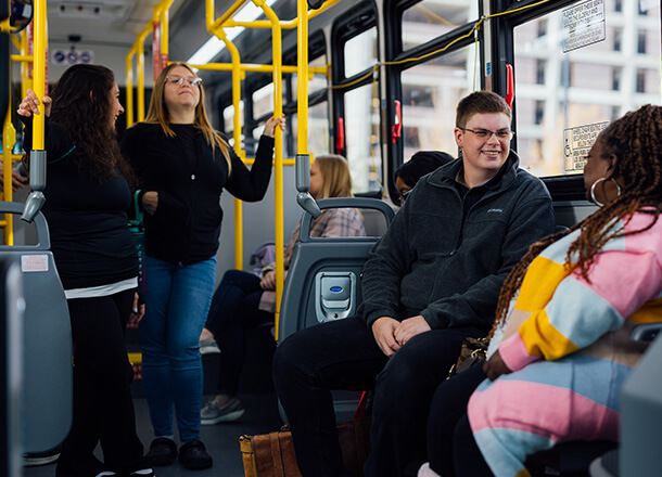 A group of young passengers socializing and smiling inside a DART bus